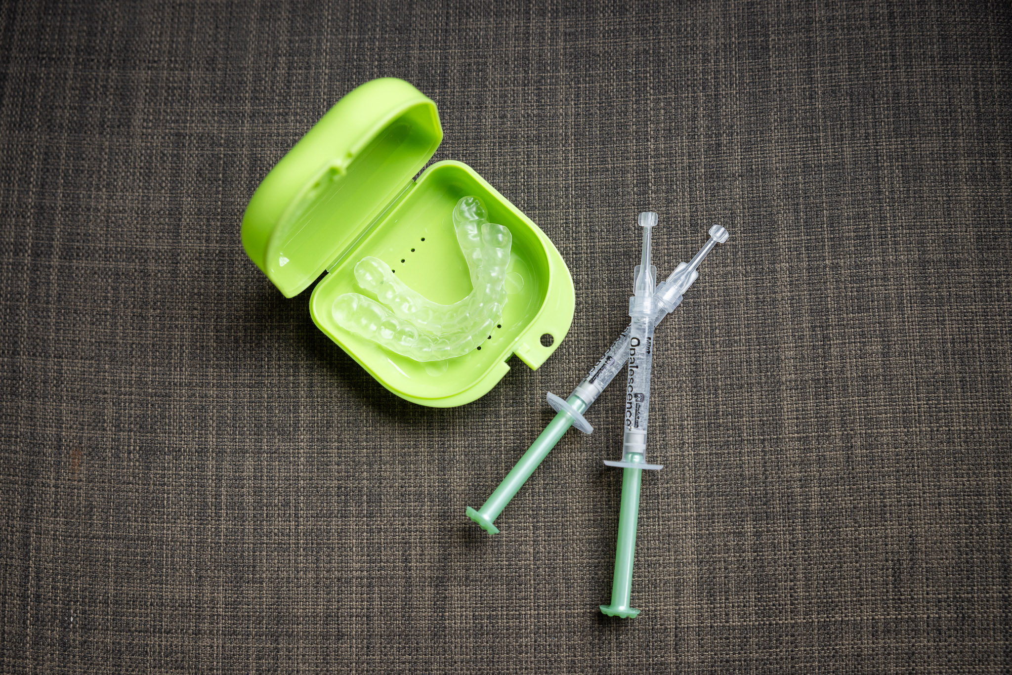 A dental nightguard in its neon green case alongside dental syringes, representing services at Ireland Restorative Dentistry