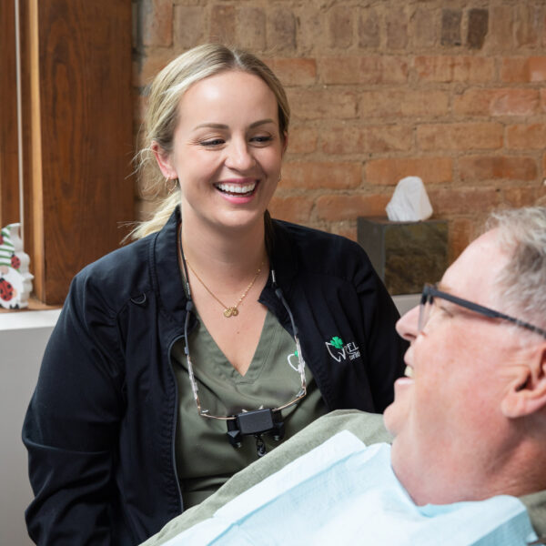 A smiling clinician at Ireland Restorative Dentistry warmly engaging with a patient before their procedure