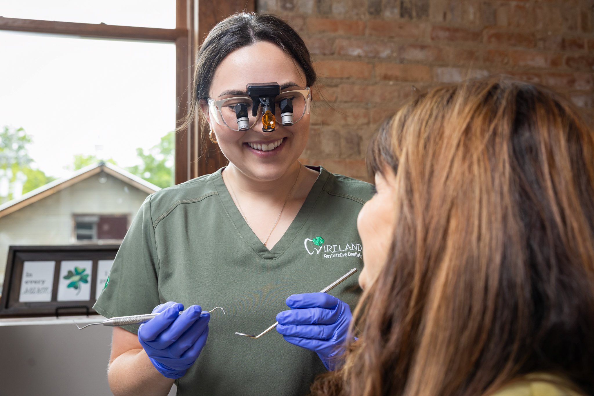 A dental hygienist in Ireland Restorative Dentistry scrubs and magnification loupes, ready to treat a patient