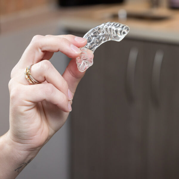 A clear dental aligner tray held up to show the custom fit offered at Ireland Restorative Dentistry