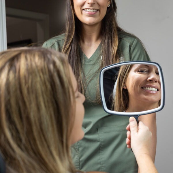 A team member at Ireland Restorative Dentistry showing a patient their smile using a hand mirror