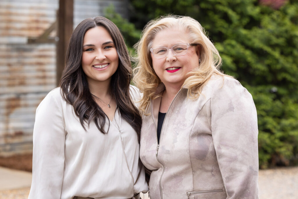 Two Ireland Restorative Dentistry team members sharing a candid smile in an outdoor setting