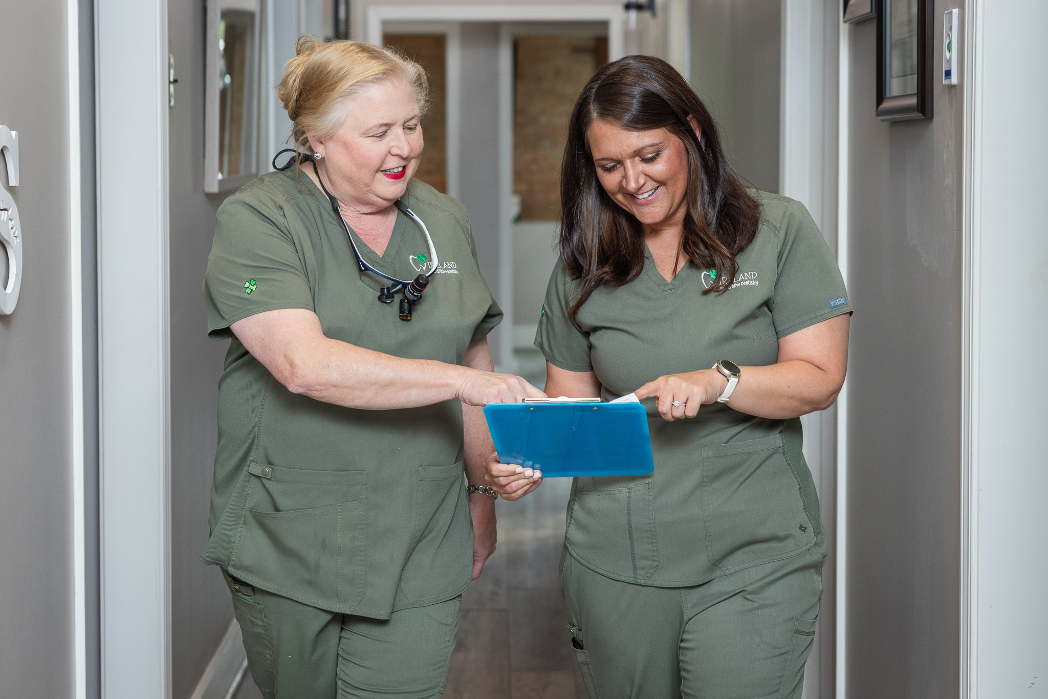 Dr. Ireland reviewing a patient chart with a team member while walking through the office hallway